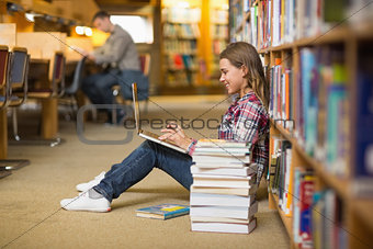 Smiling student using laptop on library floor
