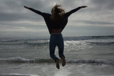 Full length rear view of a woman jumping at beach