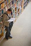 Student reading a book standing in library