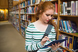 Focused student using tablet standing in library