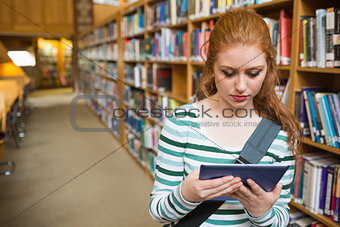 Serious student using tablet standing in library