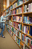 Redhead student taking book from bookshelf in the library