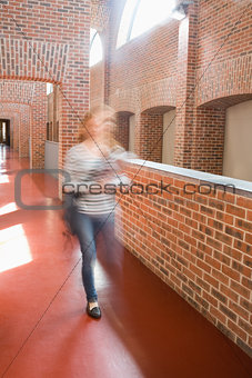 Young student rushing in the hall holding folders