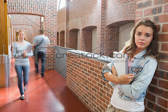 Student leaning against wall in the corridor looking at camera
