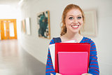 Smiling student holding folders in the hall