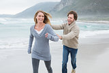 Cheerful couple running at beach