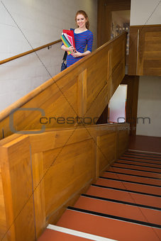 Happy student holding folders on the stairs looking at camera