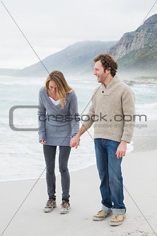 Happy casual couple holding hands at beach