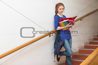 Redhead student reading notes on the stairs
