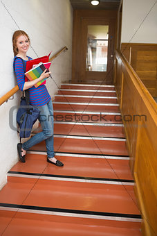 Happy young student holding her notes on the stairs