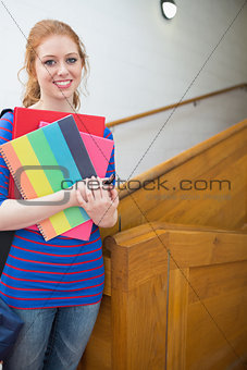 Pretty student standing on the stairs smiling at camera