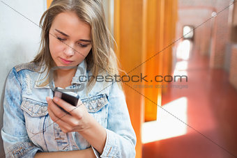 Pretty student standing in the hall sending a text