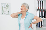 Senior woman suffering from neck pain in medical office