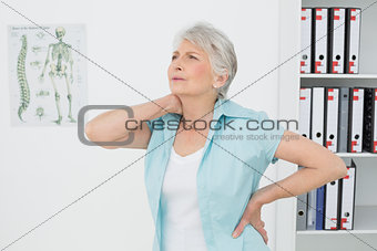 Senior woman suffering from neck pain in medical office
