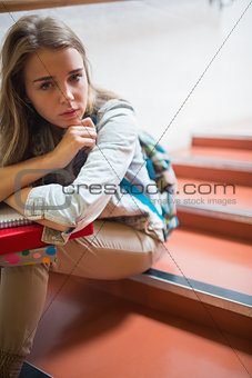 Troubled lonely student sitting on stairs looking at camera