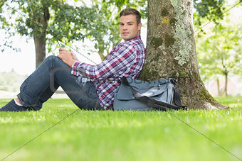 Smiling student using his tablet to study outside
