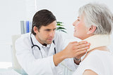 Male doctor examining a senior patient's neck
