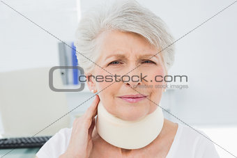 Senior woman wearing cervical collar in medical office