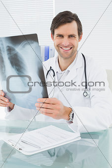 Smiling doctor with lungs x-ray in medical office