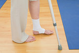 Low section of a woman with crutch and bandaged leg