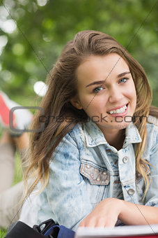 Smiling young student lying on grass