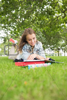 Smiling young student studying on the grass