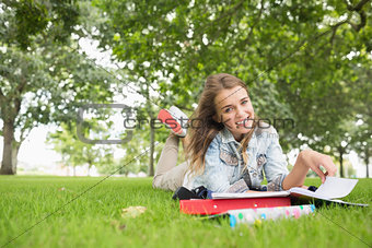 Cheerful young student studying on the grass