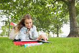 Happy student lying on the grass studying