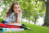 Young pretty student lying on the grass on the phone