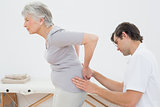 Physiotherapist examining senior woman's back