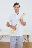 Portrait of a confident doctor holding skeleton model