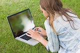 Student lying on the grass using her laptop