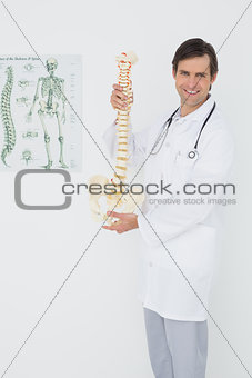 Smiling male doctor holding skeleton model