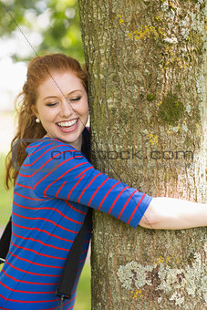Laughing redhead hugging a tree