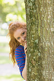 Pretty redhead hiding behind a tree