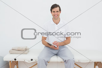 Smiling male trainer with clipboard in hospital gym