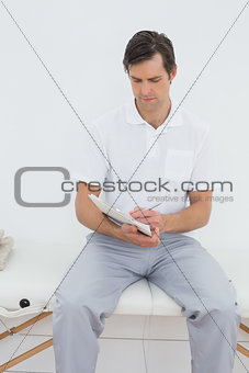 Trainer with clipboard sitting at hospital gym