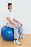 Young man sitting on exercise ball in hospital gym
