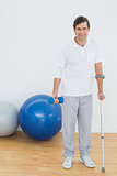 Portrait of a smiling man with crutch and dumbbell