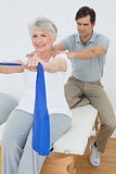 Male therapist assisting senior woman with exercises