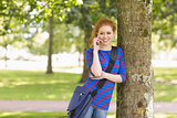 Happy student leaning against a tree talking on the phone