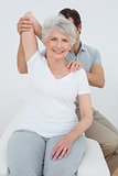 Physiotherapist stretching a smiling senior woman's arm