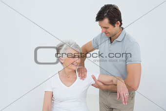Physiotherapist massaging a smiling senior woman's arm