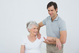 Physiotherapist massaging a smiling senior woman's arm