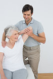 Physiotherapist stretching a smiling senior woman's arm
