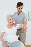 Male physiotherapist stretching a senior woman's arm