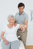 Male physiotherapist stretching a senior woman's arm