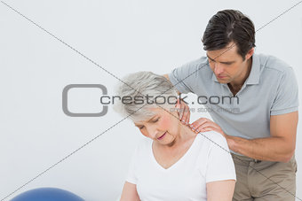 Physiotherapist massaging a senior woman's neck