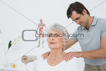 Male physiotherapist massaging a senior woman's shoulders