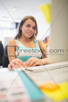 Pretty smiling girl doing assignment in the computer room